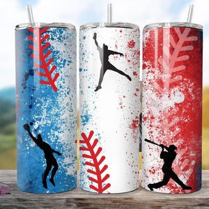 Pode incluir: Três canecas com tema de beisebol com tampas e canudos. Cada caneca apresenta um design diferente: uma com fundo salpicado azul e branco, uma com fundo branco e outra com fundo salpicado vermelho e branco. Apresentam-se silhuetas de jogadores de beisebol.