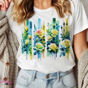 May include: White t-shirt with a watercolor design of yellow roses and green leaves on a blue and yellow background.