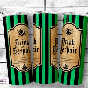 Op de afbeelding: Drie groene en zwarte gestreepte roestvrijstalen bekers met een vintage label met de tekst "Drink of Despair". Het label heeft een heks op een bezem en een ketel.