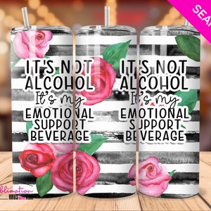 May include: A white tumbler with black and white stripes and pink roses. The tumbler has the text "It's not alcohol, it's my emotional support beverage" on it.