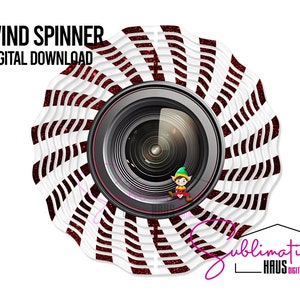 Puede incluir: Molino de viento a rayas rojas y blancas con un diseño de lente de cámara. El molino de viento tiene un acabado brillante y presenta una pequeña figura de elfo.