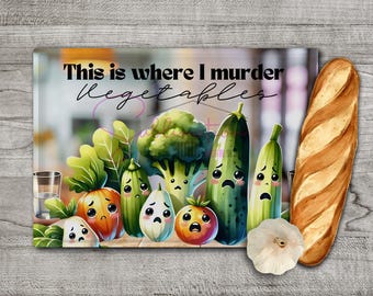 May include: A white cutting board with the text "This is where I murder vegetables" in black lettering. The board features a cartoon illustration of various vegetables with faces, including a green broccoli, a green zucchini, a green cucumber, a yellow squash, a red tomato, and a white onion.