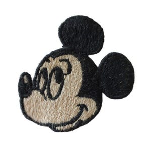 以下が含まれることがあります： ミッキーマウスの頭の黒と白の刺繍パッチ。ミッキーは目を閉じて笑顔で、耳は黒です。