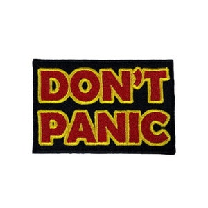May include: A black fabric patch with yellow stitching around the edges. The patch says "DON'T PANIC" in red letters with a yellow outline.