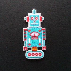 May include: A turquoise blue robot with red and white accents. The robot has a round head with two red eyes and a white smile. The robot has a white body with red and white stripes. The robot has a white base with four red circles.