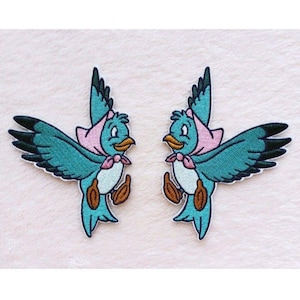 May include: Two embroidered iron-on patches of blue birds wearing pink bonnets. The birds are flying with their wings spread out.