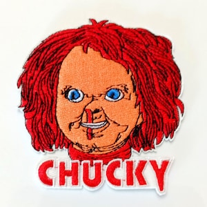 Può includere: Toppa ricamata raffigurante il volto di Chucky, con capelli rossi, occhi blu e un'espressione cucita. La toppa include il nome "CHUCKY" in lettere rosse con bordo bianco, per i fan dei film horror.