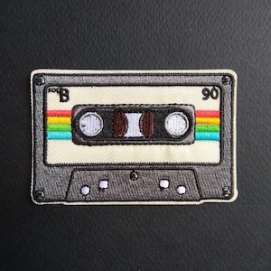 May include: A vintage-style cassette tape patch with a black and grey design. The tape is labelled "B" and "90".