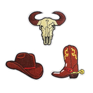 Puede incluir: Tres parches bordados para planchar que representan un sombrero de vaquero, un par de botas de vaquero y una calavera de toro. Los parches son todos marrones y rojos.