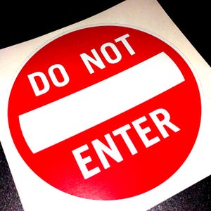 Puede incluir: Una pegatina redonda roja con las palabras "DO NOT ENTER" en blanco. Una barra horizontal blanca divide el círculo. La pegatina está sobre un fondo blanco.