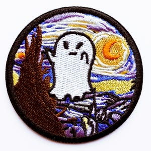 Puede incluir: Parche bordado con un fantasma blanco con expresión enfadada sobre un fondo de cielo estrellado. El diseño incluye una luna creciente y un árbol, todo dentro de un borde negro circular. Para ropa o accesorios.