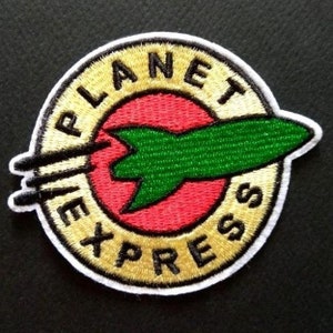 May include: Embroidered patch featuring the words "PLANET EXPRESS" in gold lettering around a red circle. A green rocket ship is in the center. The patch has a white border and is likely for clothing or accessories.
