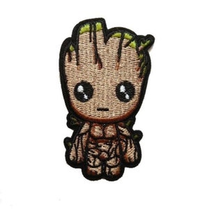 May include: Iron-on patch featuring an embroidered cartoon character with brown skin, green hair, and large eyes. The character is wearing a brown and green outfit.