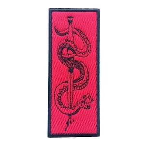 Könnte beinhalten: Schwarzer gestickter Aufnäher mit rotem Hintergrund. Der Aufnäher zeigt eine Schlange, die sich um einen Dolch windet.