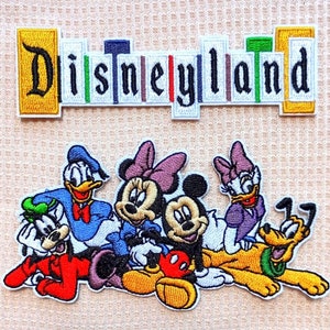 May include: An embroidered patch featuring the iconic Disneyland logo with a colorful design. The patch features Mickey Mouse, Minnie Mouse, Donald Duck, Goofy, Pluto, and Daisy Duck.