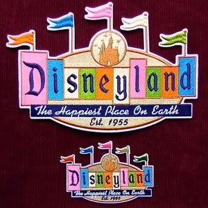 Puede incluir: Dos parches bordados con el logotipo de Disneyland. El parche más grande es un letrero colorido con el texto "Disneyland" en una fuente estilizada, "The Happiest Place On Earth" y "Est. 1955". El parche más pequeño es un diseño similar pero más pequeño.