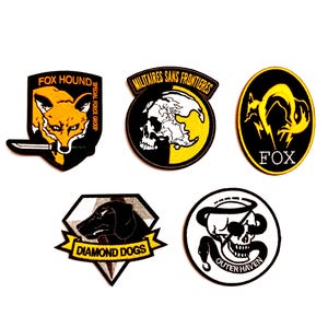 May include: A collection of six embroidered patches with various designs. The patches feature a fox, skull, and dog, with text including "FOX HOUND", "MILITAIRES SANS FRONTIERES", "FOX", "DIAMOND DOGS", and "OUTER HAVEN".