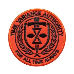May include: A circular orange patch with black embroidery. The patch features a shield with a sword, an hourglass, and two eyes. The text around the shield reads "Time Variance Authority" and "For All Time Always".
