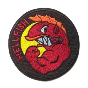 May include: A black and red embroidered patch with the text "HELLFISH" in a circular design. The patch features a red cartoon fish with a yellow mouth, a red arm, and a red fin.