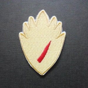 May include: Embroidered patch in a leaf shape with a light yellow background and a red diagonal stripe. The patch has a white border and is likely for clothing or accessories.