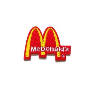 May include: Embroidered patch featuring the McDonald's logo. The patch has a red background with yellow arches and the McDonald's name in white. The patch is a rectangular shape.