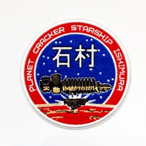 May include: Circular patch with a red border and white text that reads "PLANET CRACKER STARSHIP ISHIMURA." The center features a blue background with white stars and Japanese characters. A detailed spaceship graphic is at the bottom.