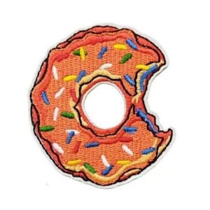 Puede incluir: Una dona rosa y naranja con chispas de colores, un bocado sacado del lado.