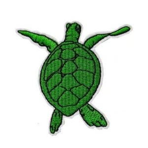 以下が含まれることがあります： 白い縁取りのある、緑色の刺繍されたウミガメのパッチ。カメは手を広げ、質感のある甲羅のデザインをしています。このパッチは、衣類やアクセサリーに適しています。