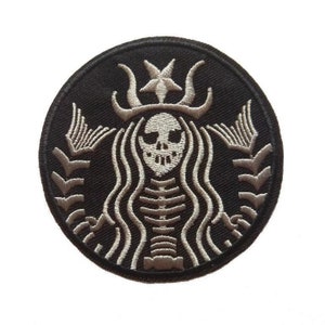 May include: A black and white embroidered patch featuring a skeleton with a skull face in a stylized version of the Starbucks logo.