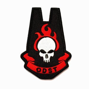 May include: Black patch with a white skull encircled by red flames. A red banner at the bottom reads "ODST". The patch has a unique shape with a notched top.
