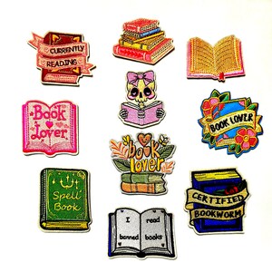 以下が含まれることがあります： 本をテーマにした10種類の刺繍ワッペン。本の積み重ね、開いた本、読書をする頭蓋骨、そして「Currently Reading」「Book Lover」「Spell Book」「Certified Bookworm」「I read banned books」と書かれたテキストバナーが含まれています。