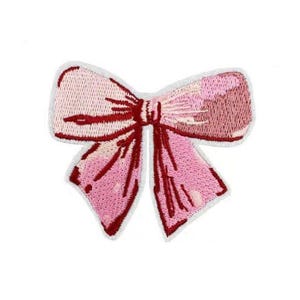 Op de afbeelding: Een geborduurde strik in roze en rood met een witte omtrek. De strik is een decoratieve patch die op stof kan worden gestreken.