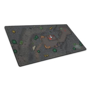 May include: A rectangular tabletop gaming mat featuring a printed grid map of a dark, rocky landscape. The design includes a central stone structure with interior furniture, surrounded by scattered green bushes, grey boulders, and dark terrain.