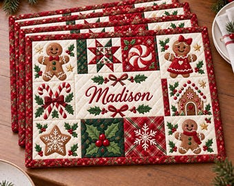 May include: A rectangular quilted placemat featuring a festive Christmas theme with gingerbread people, candy canes, a gingerbread house, snowflakes, and holly berries. The center displays the name Madison in red script surrounded by bows.