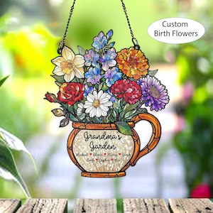 May include: A hanging floral decoration featuring a bouquet of colorful flowers in a decorative teacup-shaped vase. The text "Grandma's Garden" is displayed, along with names. The words "Custom Birth Flowers" are also visible.