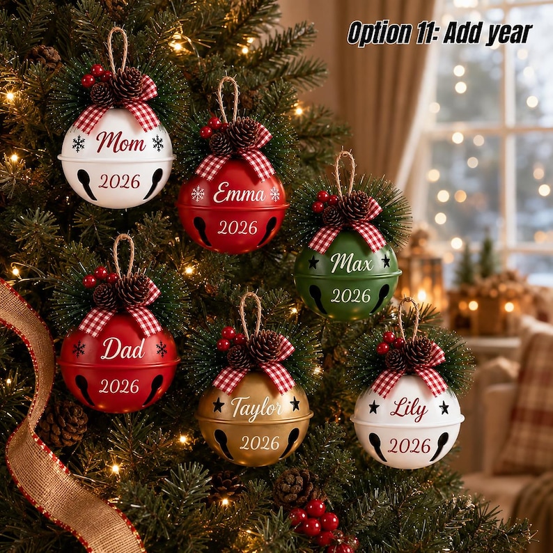 May include: Six round metal bell ornaments hanging on a Christmas tree. Each bell features a red and white gingham bow, pinecones, and red berries. The bells are white, red, green, and gold, personalized with names and the year 2026.