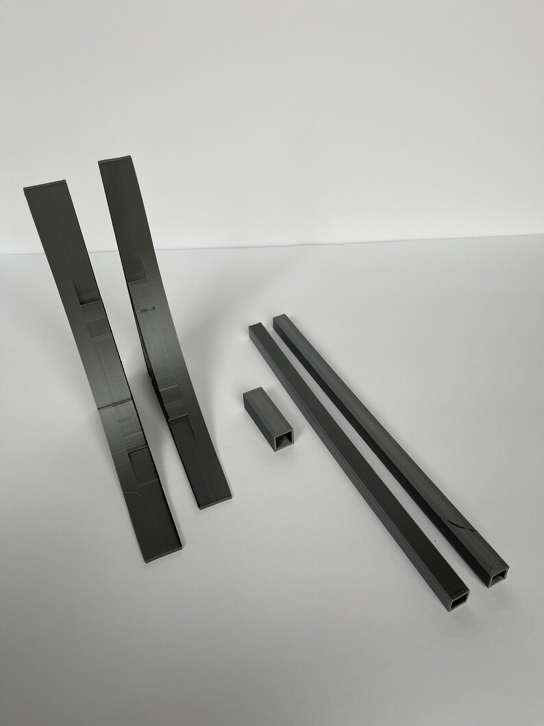 May include: A set of five 3D printed pieces in gray plastic. The set includes two curved pieces, two long straight pieces, and one small square piece.