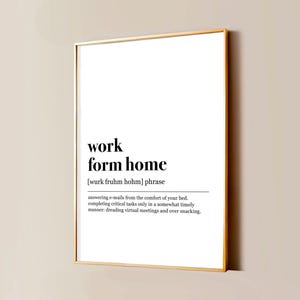 Op de afbeelding: Een verticale rechthoekige wandprint in een dunne gouden lijst met een witte achtergrond en zwarte tekst. De tekst luidt: work form home [wurk fruhm hohm] phrase, gevolgd door een definitie over het beantwoorden van e-mails vanuit bed en snacken.