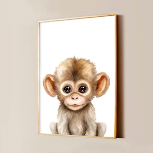 Op de afbeelding: Een ingelijste kunstdruk met een aquarelillustratie van een kleine aap met grote donkere ogen, lichtbruine vacht en opvallende oren, tegen een witte achtergrond in een dunne goudkleurige rechthoekige lijst.