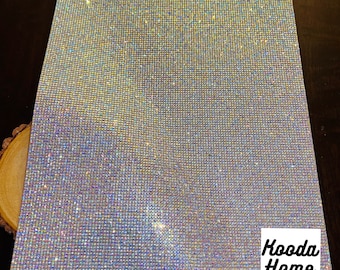 May include: A sheet of iridescent, clear rhinestones, perfect for crafting and decorating. The rhinestones are arranged in a grid pattern and have a subtle sparkle.