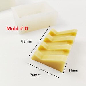Op de afbeelding: Een mal met het label "Mold # D" voor het maken van een rechthoekige zeep met vier ribbels. De mal is 9,5 cm lang, 7 cm breed en 3,5 cm hoog.