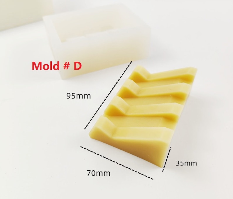 Op de afbeelding: Een mal met het label "Mold # D" voor het maken van een rechthoekige zeep met vier ribbels. De mal is 9,5 cm lang, 7 cm breed en 3,5 cm hoog.