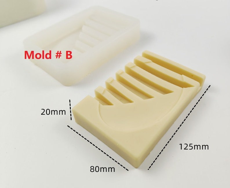 Op de afbeelding: Een beige siliconen mal voor het maken van zeep of hars ambachten. De mal is gevormd als een halve maan met vijf ribben. De mal is 80 mm breed, 125 mm lang en 20 mm diep. De tekst "Mold # B" is op de mal gedrukt.