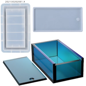 May include: A clear blue rectangular box with a black frame and a clear lid. The box is made of glass and has a smooth surface. The lid has a small hole in the center.