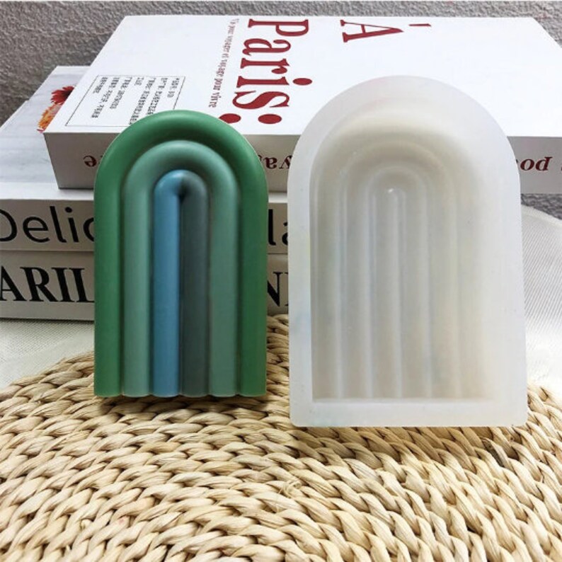 May include: Two silicone molds for making resin crafts. One mold is a light green, blue, and white rainbow arch. The other mold is a white arch with five vertical lines.