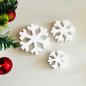 Può includere: Tre decorazioni di fiocchi di neve bianchi di diverse dimensioni. I fiocchi di neve sono realizzati in un materiale leggero e hanno un design semplice ed elegante.