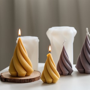 Può includere: Quattro candele decorative in una varietà di colori e forme. Due sono gialle e a forma di spirale, una è viola e a forma di spirale e una è bianca e cilindrica.