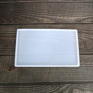 May include: A white silicone mould for resin casting. The mould is rectangular and has a smooth surface.