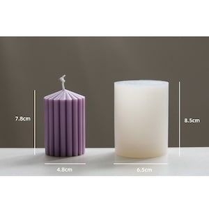 May include: Two candles, one purple and one white, with measurements in inches. The purple candle is 3.1 inches tall and 1.9 inches wide. The white candle is 3.3 inches tall and 2.6 inches wide.