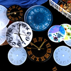May include: Assortment of clock face molds for resin crafts. The molds are made of clear silicone and feature different clock face designs, including Roman numeral, Arabic numeral, and marble-style clock faces.
